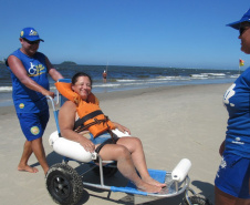 Com dificuldades extremas de caminhar, Débora Leia dos Santos tem tomado pelo menos dois banhos de mar por dia graças às cadeiras anfíbias disponibilizadas no Balneário Caieiras, no município de Guaratuba. Foto: Sanepar